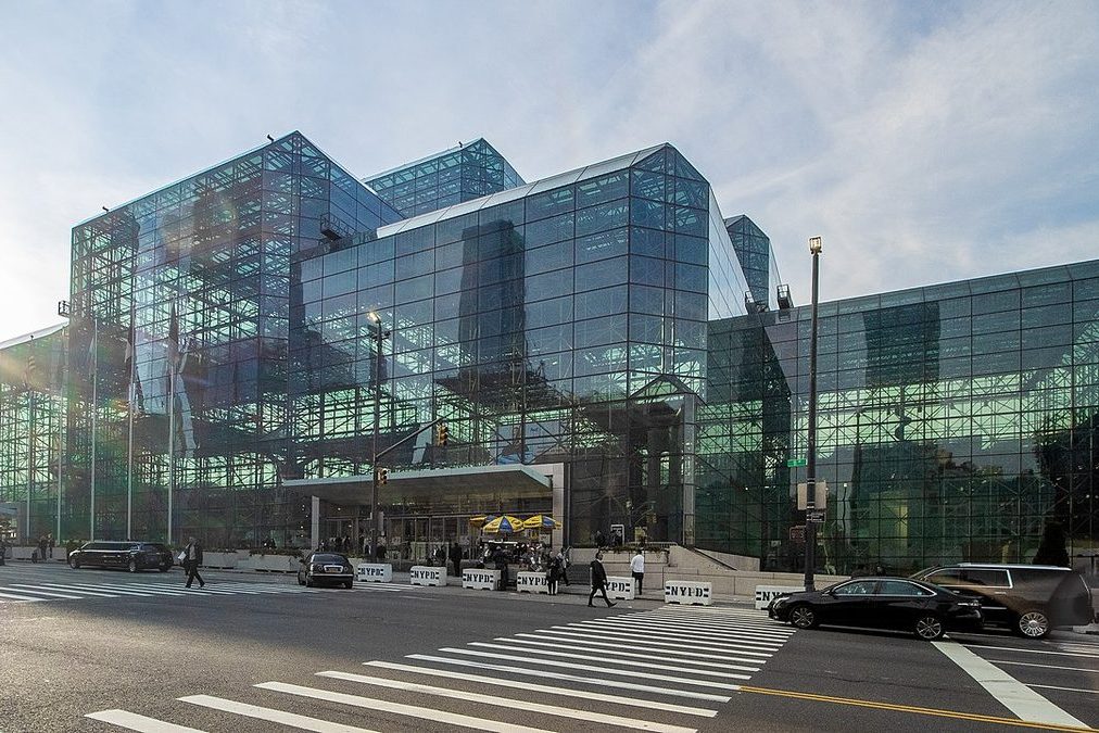 Large glass-facade New York City convention center exterior at blue hour